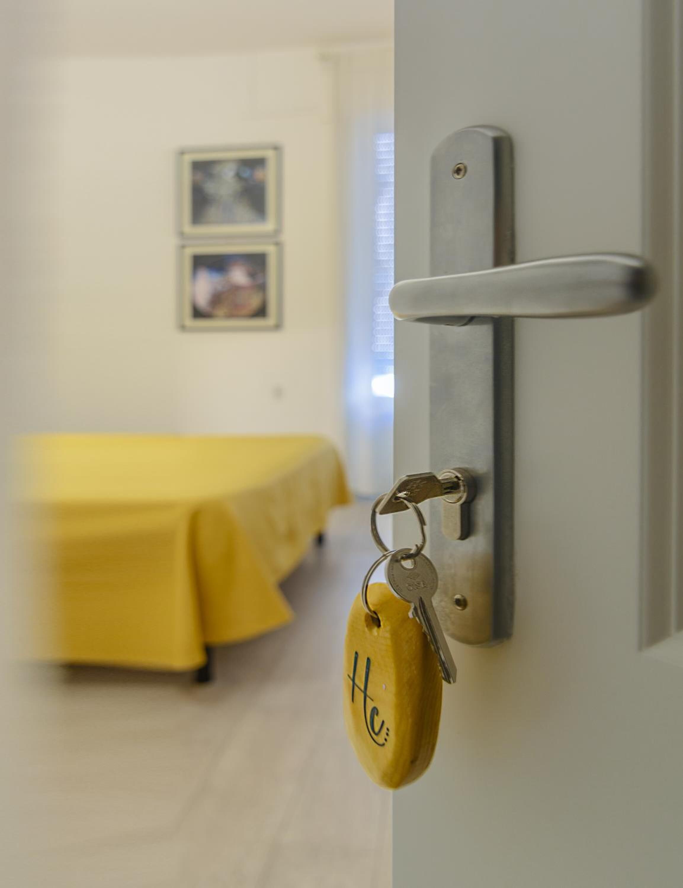 Een hotelkamer met een bed, een deur met een sleutelhanger en een lichtschakelaar aan de muur.