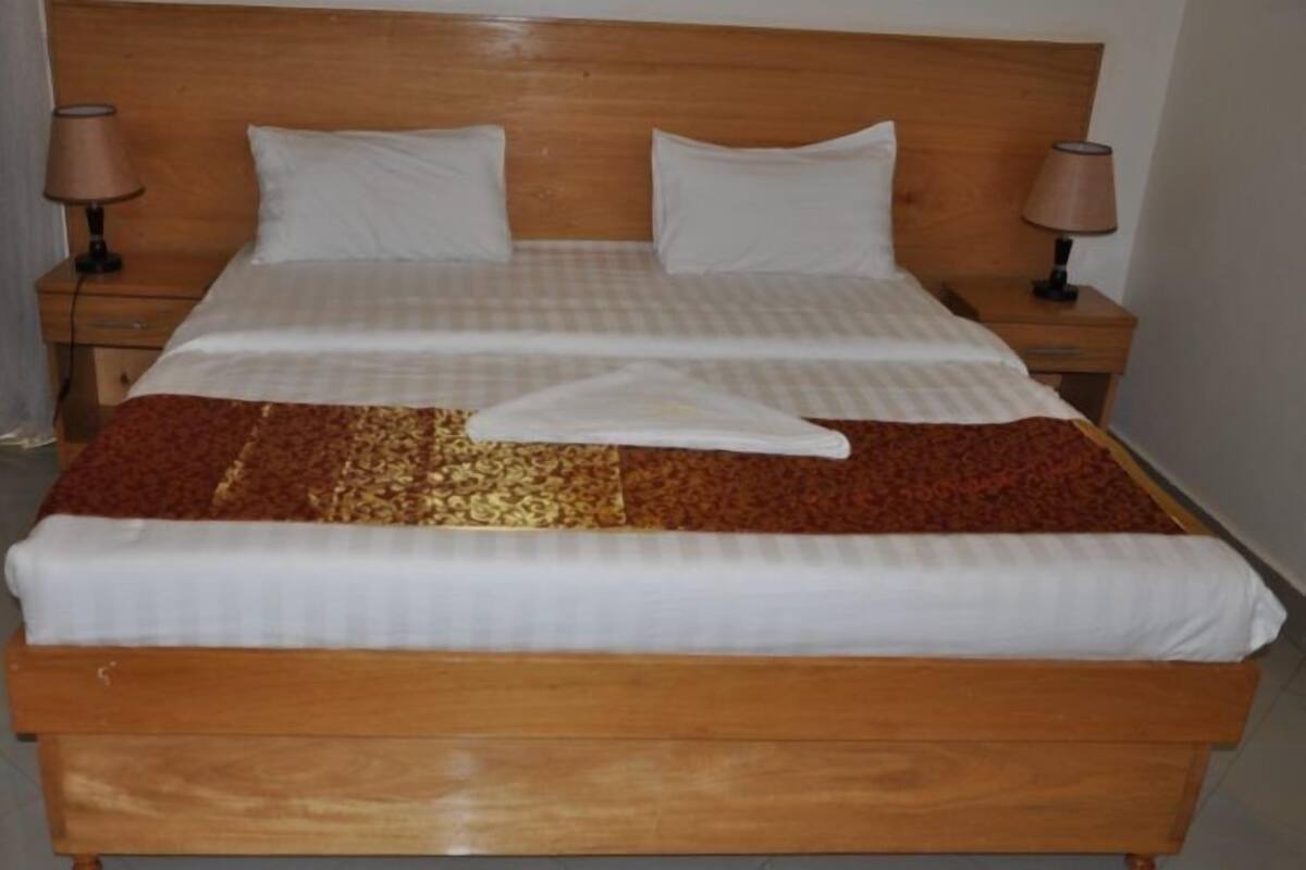 A double bed with a wooden headboard, two bedside tables with lamps, and a patterned bedspread.