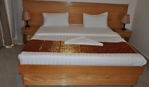 A double bed with a wooden headboard, two bedside tables with lamps, and a patterned bedspread.