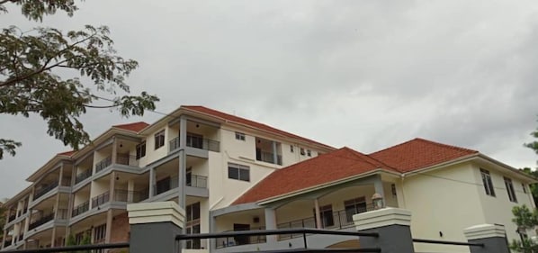 A multi-story residential building with balconies and a red-tiled roof.