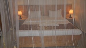 A bed with a canopy, two bedside lamps, and a wooden headboard. - EKA Hoima Hotel (Hoima)