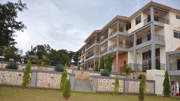 A multi-story residential building with balconies, a stone facade, and a landscaped front yard. - EKA Hoima Hotel (Hoima)