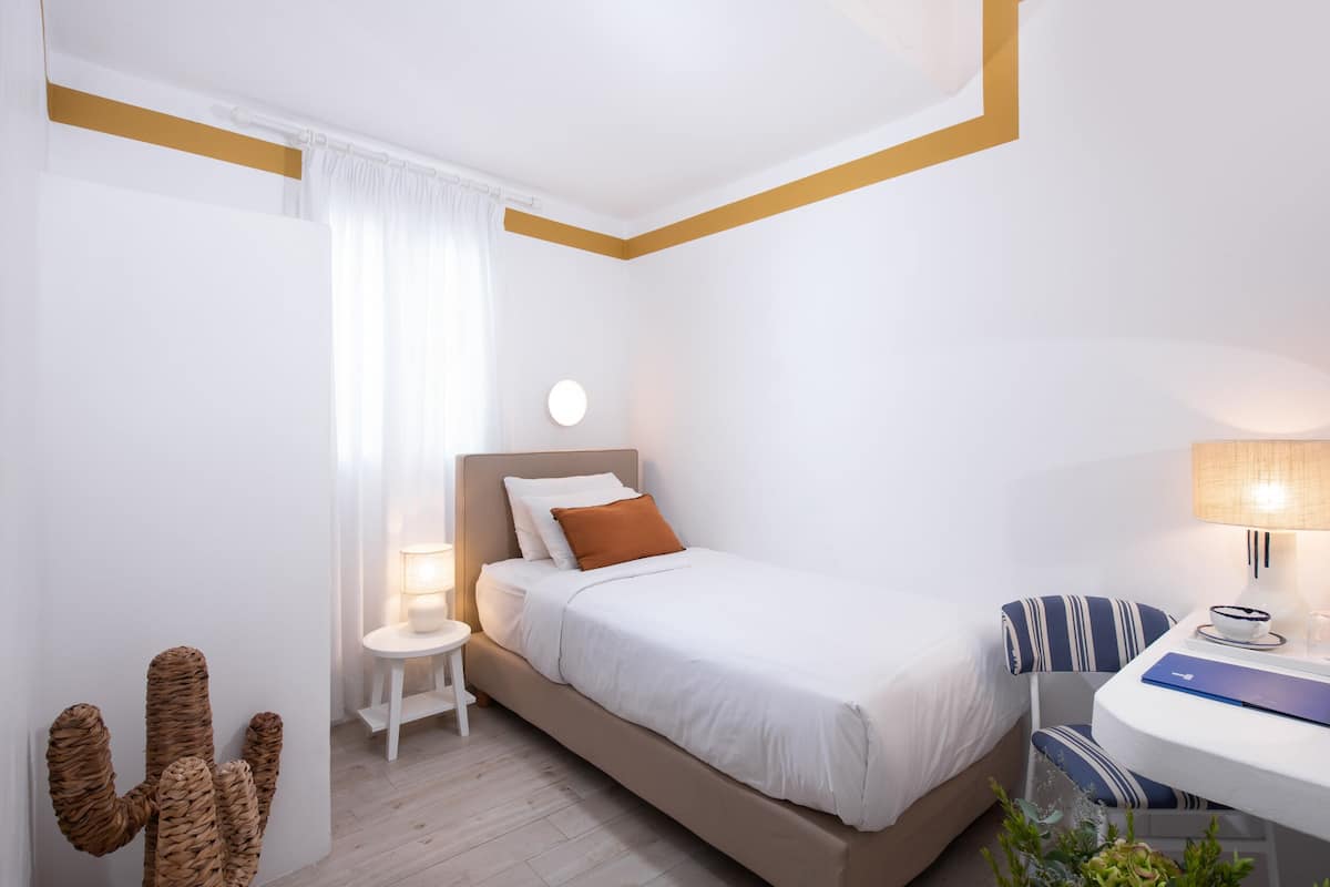 Un dormitorio con cama, mesita de noche, lámpara y una decoración de cactus.