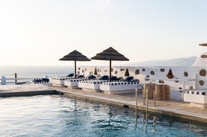 Una piscina al aire libre, sombrillas, sillones reclinables de piscina