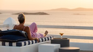 Una persona descansando en una silla lounge a rayas con vista al mar y a islas distantes.