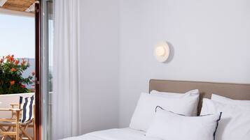 A hotel room with a bed, white bedding, a wooden headboard, a small table, and a chair.