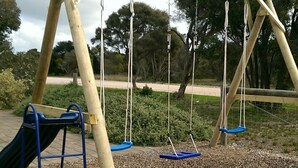 A playground with a wooden swing set and a slide.