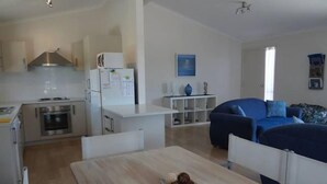 A compact living space with a kitchenette, a dining table, and a blue sofa.