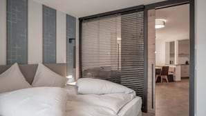 Un dormitorio moderno con una cama, un escritorio y una silla en la habitación contigua.