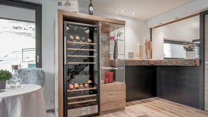 Una cocina moderna con un refrigerador para vinos, una mesa de comedor con mantel blanco y vistas al exterior.
