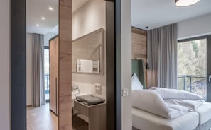 A modern bedroom with a large window, a bedside table, and a built-in wardrobe. - Corso Living (Soelden)