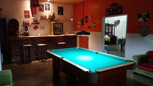 A pool table in a room with a bar area, a mirror, and various wall decorations.