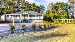 A two-story building with a porch, a small garden with a fountain, and a pergola. - Bare Foot Luxury, minutes from Maleny Town Centre (Maleny)