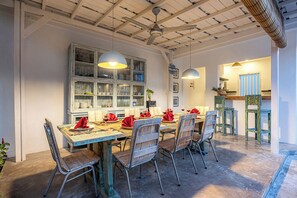 Un comedor con una mesa de madera, sillas de metal y un aparador grande con puertas de cristal.