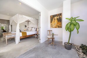 Un dormitorio con una cama con dosel, una mesita, una silla y una planta en maceta.