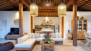 A cozy living room with a sofa, a coffee table with a plant, and a kitchen in the background. - Central Oberoi, Seminyak - Newly Refurbished Villa A (Seminyak)