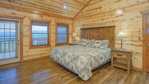 Une chambre dans une cabane en bois, avec un lit, deux tables de chevet et un ventilateur de plafond.
