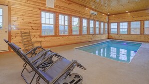 Un intérieur en bois avec une piscine, un fauteuil de relaxation et de grandes fenêtres.