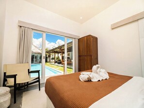 Une chambre d’hôtel avec un lit, une chaise, une armoire en bois et une vue sur une piscine et un espace extérieur.