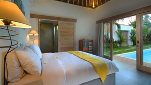 Ein Schlafzimmer mit Bett, Lampe und Blick auf einen Pool.