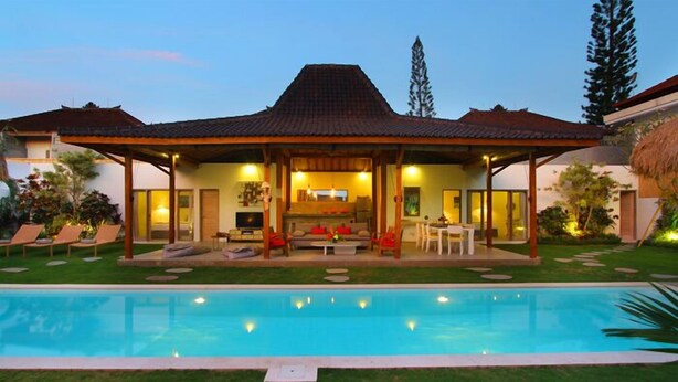 Ein zweistöckiges Haus mit Schwimmbecken davor.