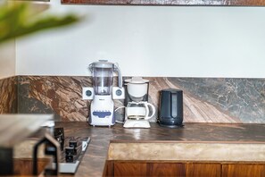 A kitchen counter with a blender, a coffee maker, and a black appliance, possibly a food processor or mixer.