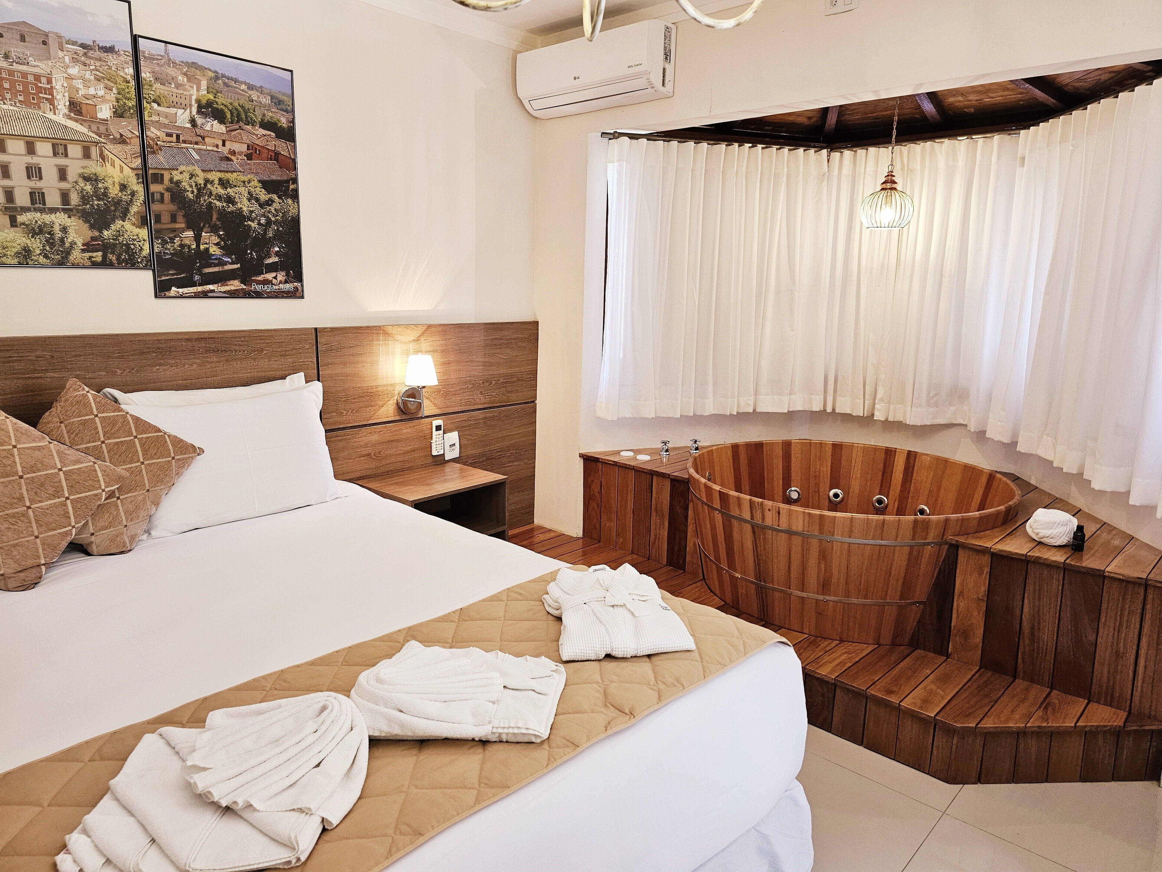 Habitación de hotel con cama, bañera de madera, mesita de noche, teléfono en la pared y ventana con cortinas.