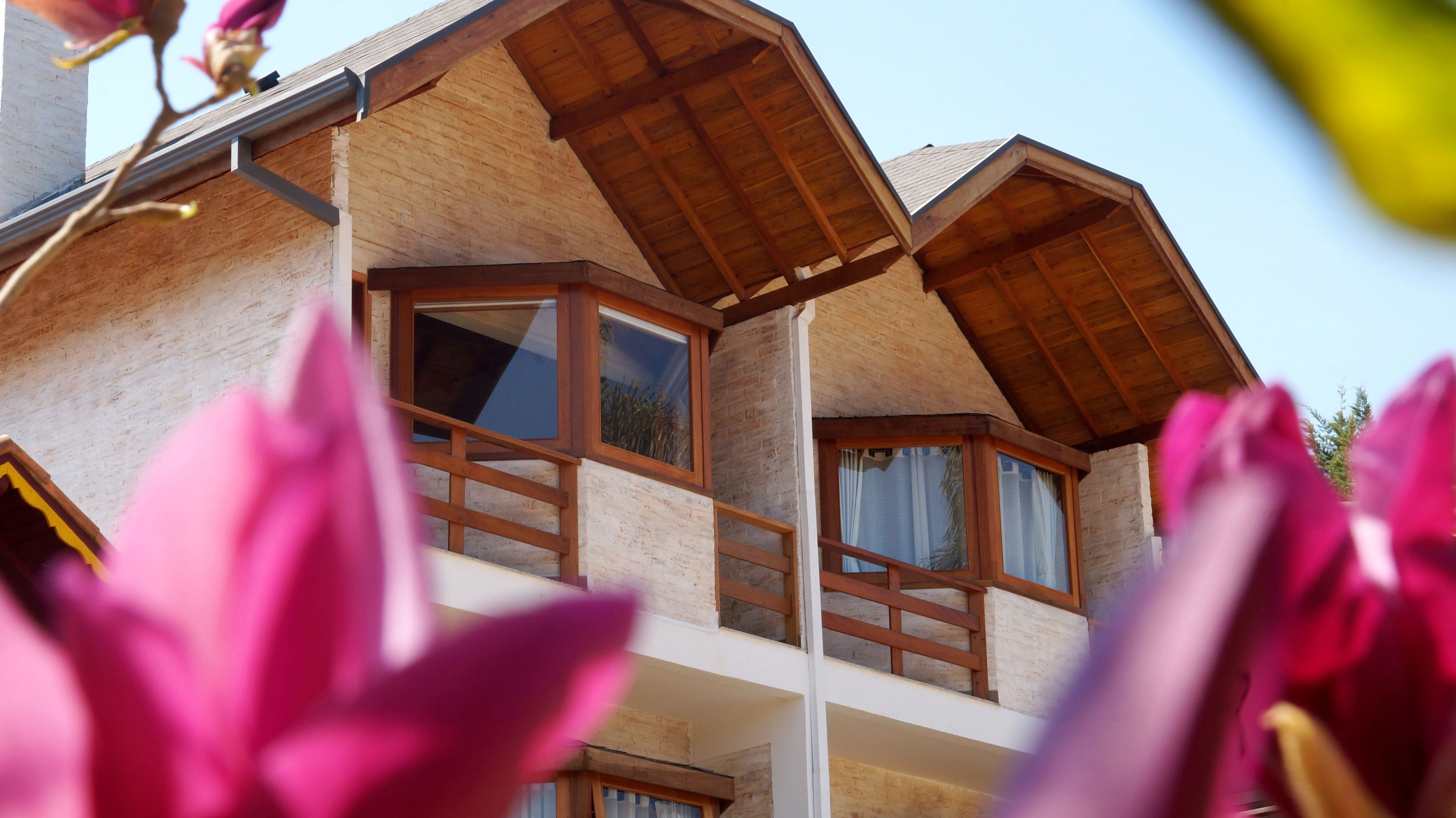 A wooden chalet with a balcony and large windows.