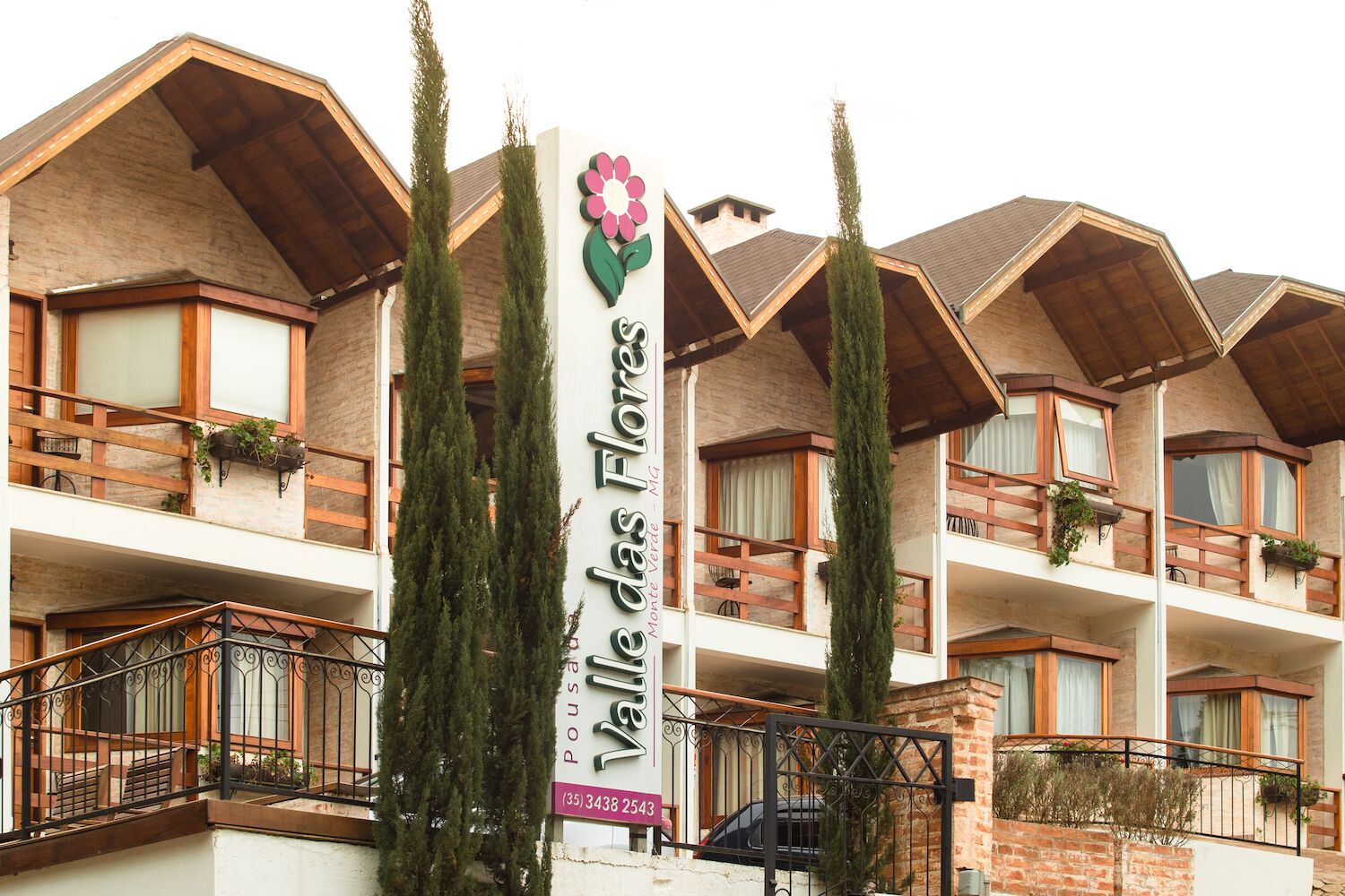 A hotel with multiple balconies, a prominent flower logo, and a contact number.