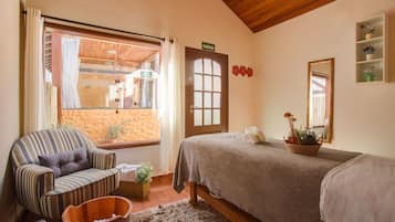 Relax in this serene bedroom with a large bed, a striped armchair, and a view of the outdoor area.
