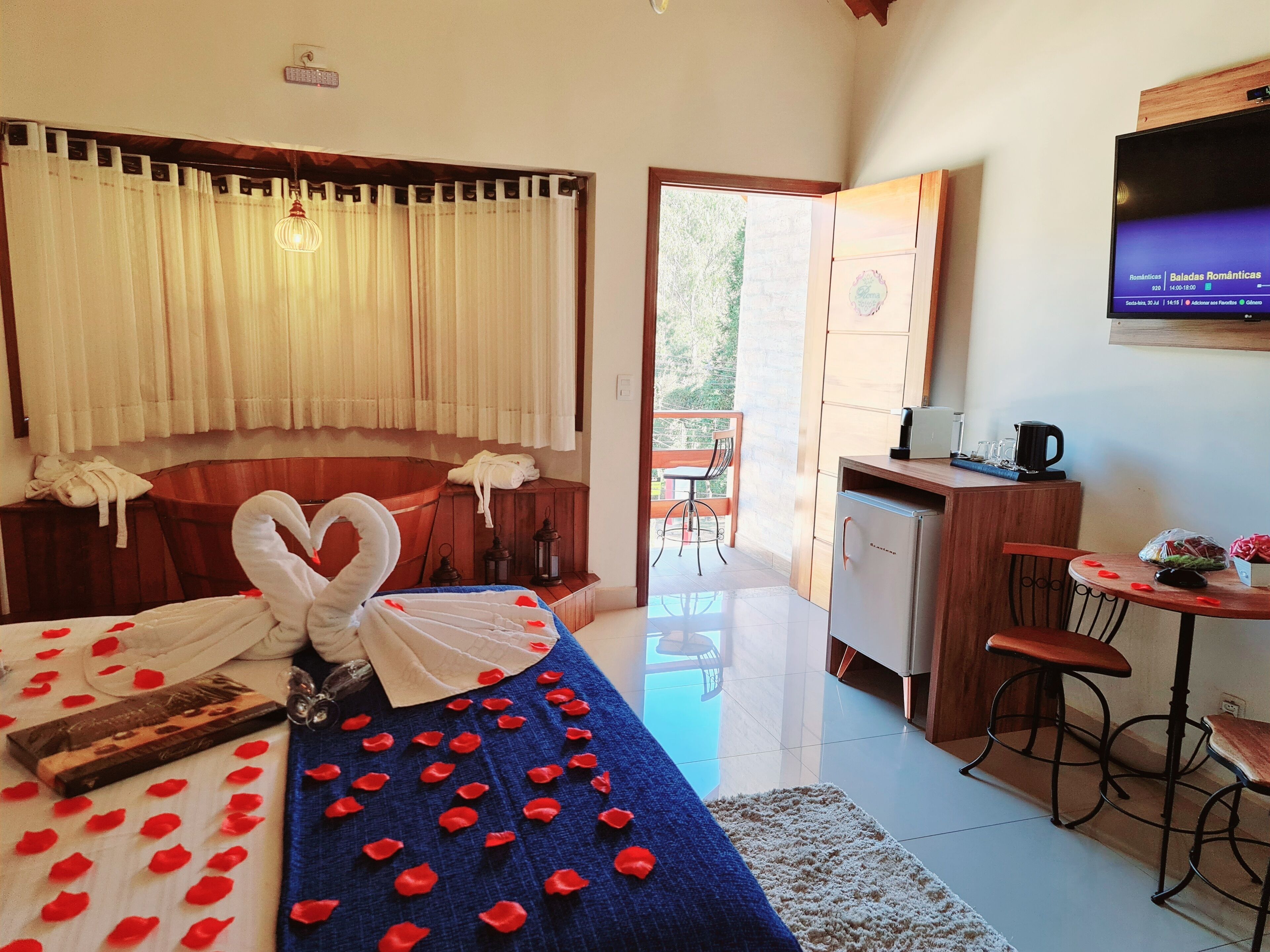Habitación de hotel con cama, escritorio, silla, una mesita y televisor en la pared.