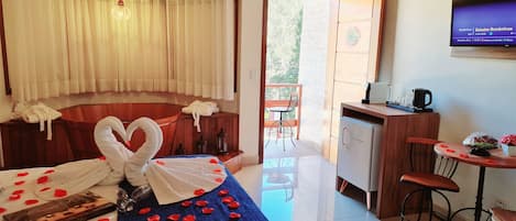 Una camera d'albergo con un letto, una scrivania, una sedia, un tavolino e una TV appesa al muro.