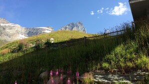 Un paisaje montañoso con cielo despejado, una ladera cubierta de hierba y una valla de madera.