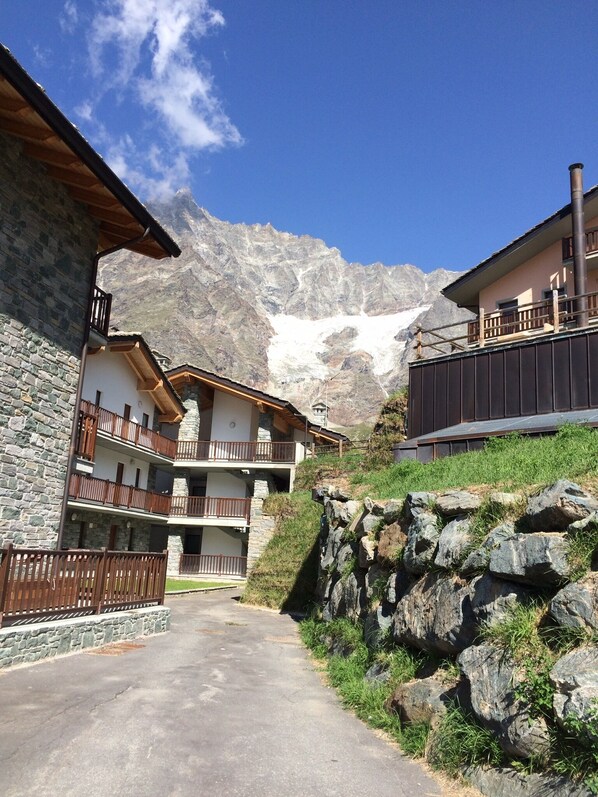A mountain lodge with stone and wood architecture, multiple balconies, and a view of snow-capped mountains.