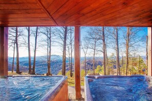 Eine Holzhütte mit zwei Whirlpools mit Blick auf ein bewaldetes Tal.