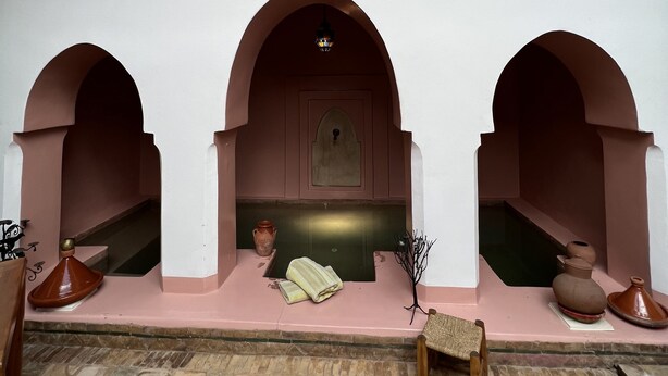 A room with a tiled floor, a bench, and a small table with a vase and a lamp. - Riad Villa El Arsa (Marrakech)