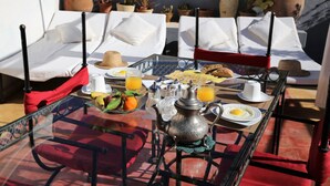 A breakfast table set with a teapot, cups, plates, and a glass of orange juice. - Riad Villa El Arsa (Marrakech)