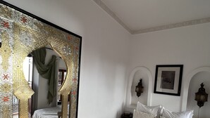 A bedroom with a large ornate mirror, a bed with white linens, and a red carpet. - Riad Villa El Arsa (Marrakech)