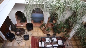 An indoor courtyard with a seating area, potted plants, and a view of the outside. - Riad Villa El Arsa (Marrakech)