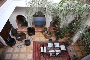 Un patio interior con zona de estar, plantas en macetas y vistas al exterior.