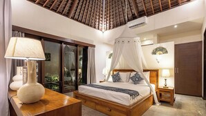 A bedroom with a canopy bed, a wooden nightstand, a bedside table with a lamp, and a large window with curtains. - Villa Tigamangga Central Seminyak Oberoi 10mn walk (Seminyak)