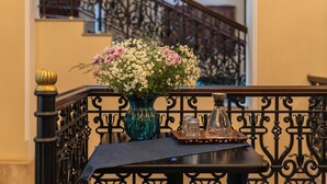 A staircase with a black railing and a vase of flowers on a table at the landing. - Hotel Bella Casa (Tbilisi)
