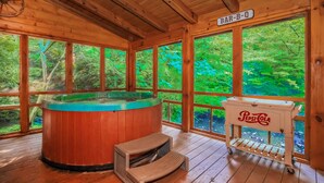 A wooden cabin with a hot tub, a bar cart, and a sign reading "BAR-B-Q". - Creekside Getaway: Top Amenities, Game Room, Fire Pit area on the creek, Ample Parking, Gatlinburg! (Pigeon Forge)