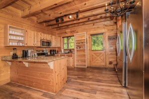Cocina de cabaña de madera con una isla central, electrodomésticos de acero inoxidable y estanterías empotradas.