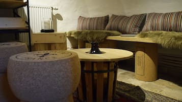 Um quarto acolhedor com uma mesa de madeira, um banquinho redondo, um sofá com almofadas listradas e um cobertor de pele.