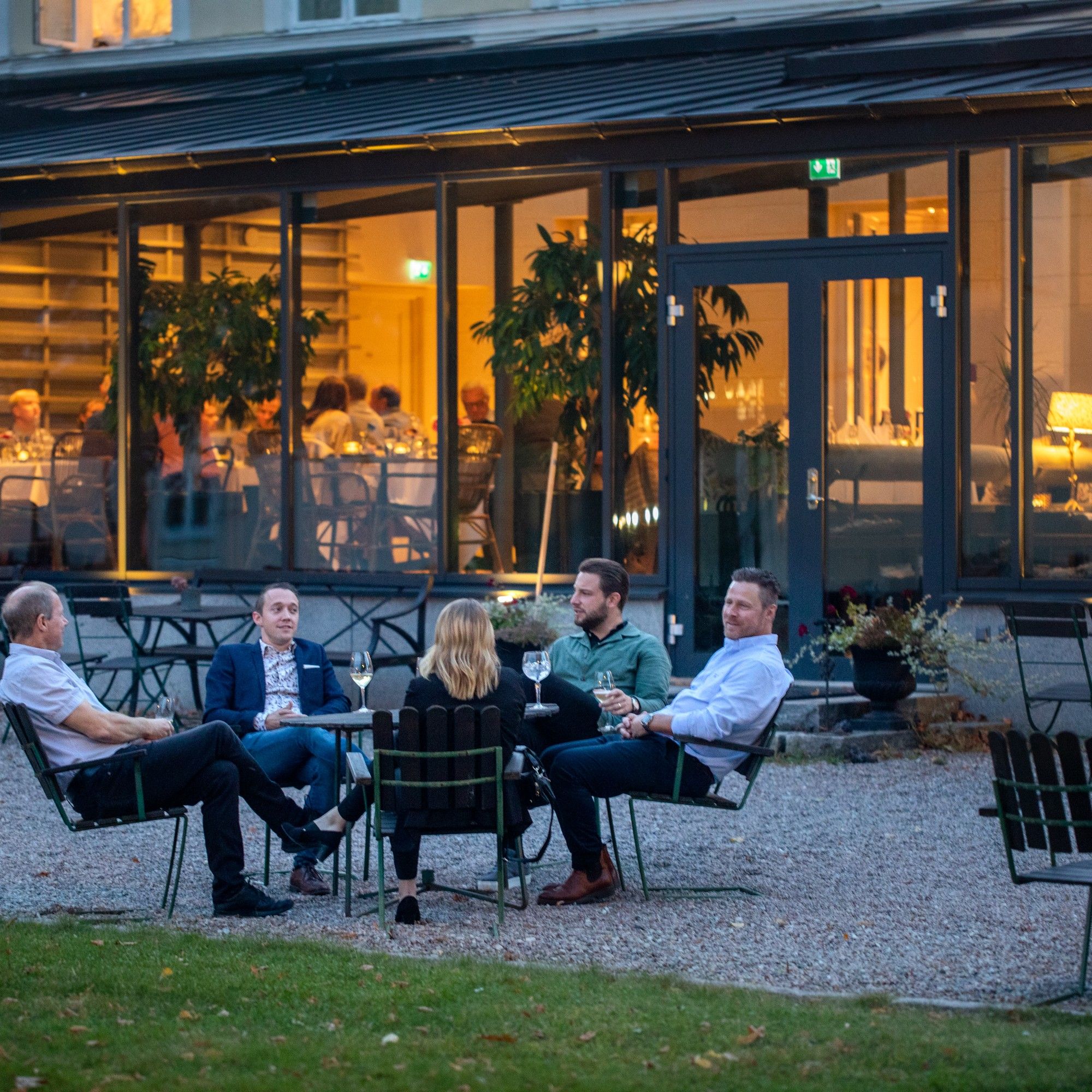 A group of people seated at an outdoor table with a view of a building in the background.