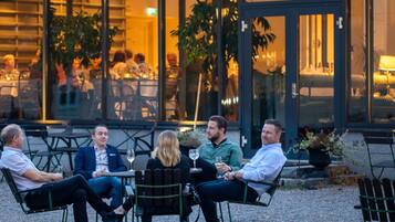 A group of people seated at an outdoor table with a view of a building in the background.
