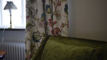 Et værelse med en radiator, en lampe og en grøn sofa.