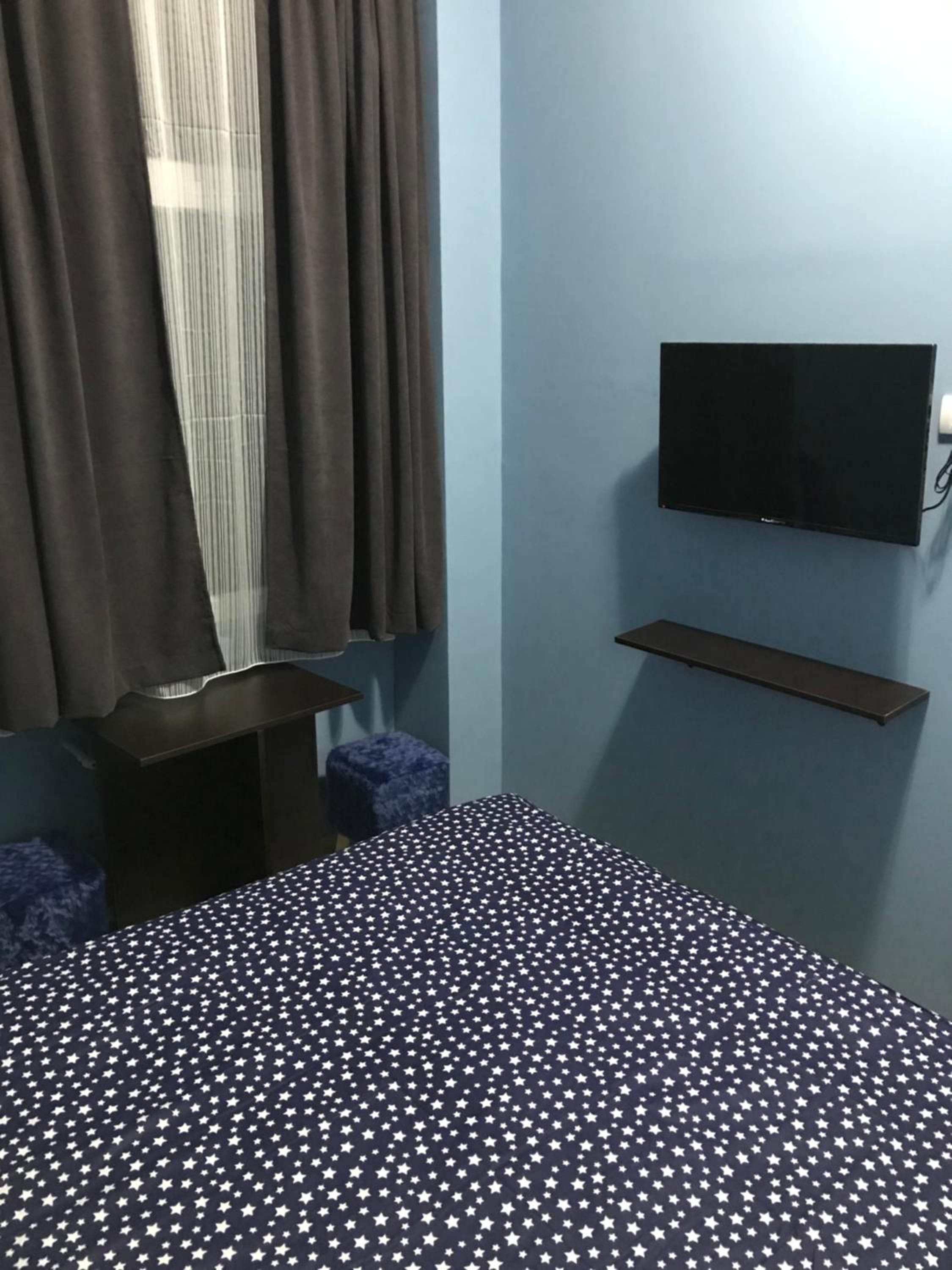 A bedroom with a bed, a TV mounted on the wall, a small table, and a chair.