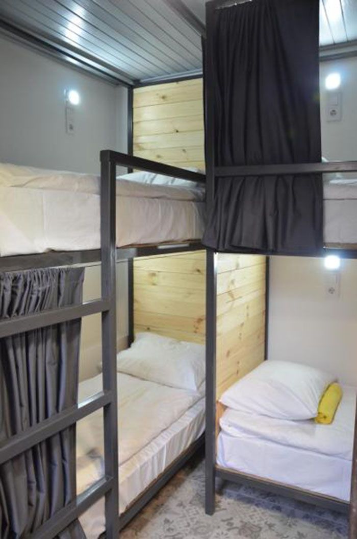 A bunk bed room with a wooden headboard, a curtain, and a small window.